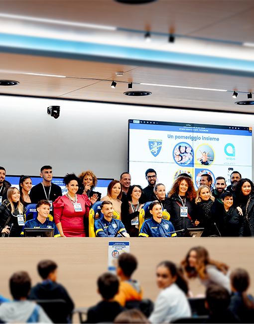 Partecipanti all'evento "Un pomeriggio insieme" presso lo stadio Benito Stirpe di Frosinone posano per uno scatto con tre giocatori del Frosinone nella sala stampa dello stadio